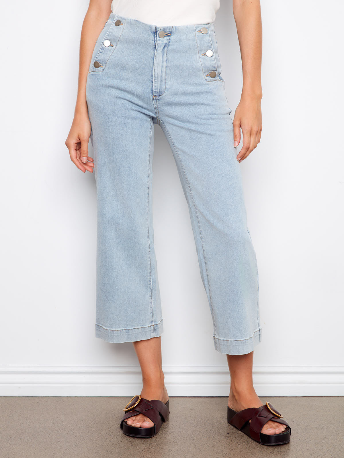 Charlie B Triple Threat 26” Denim Capris in light wash denim with button details on pockets, styled with dark sandals.