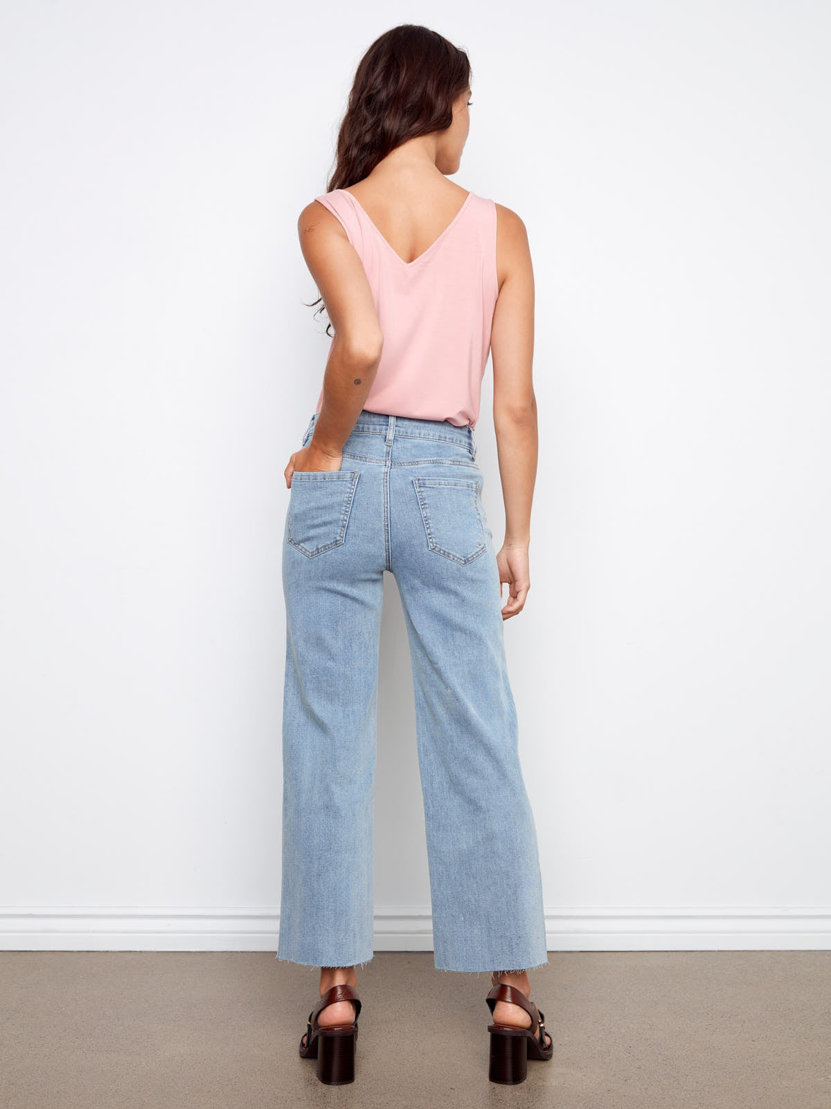 Light wash denim Charlie B Embroidered Flower 27” Wide Denim Jeans paired with a pink sleeveless top and black heels.