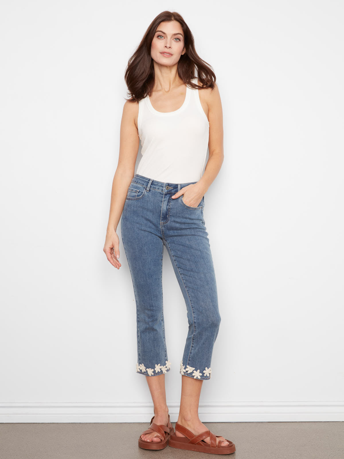 Charlie B Crochet Flower Hem Denim Capris in medium blue denim with floral trim at hem by Charlie B, styled with white tank and sandals.