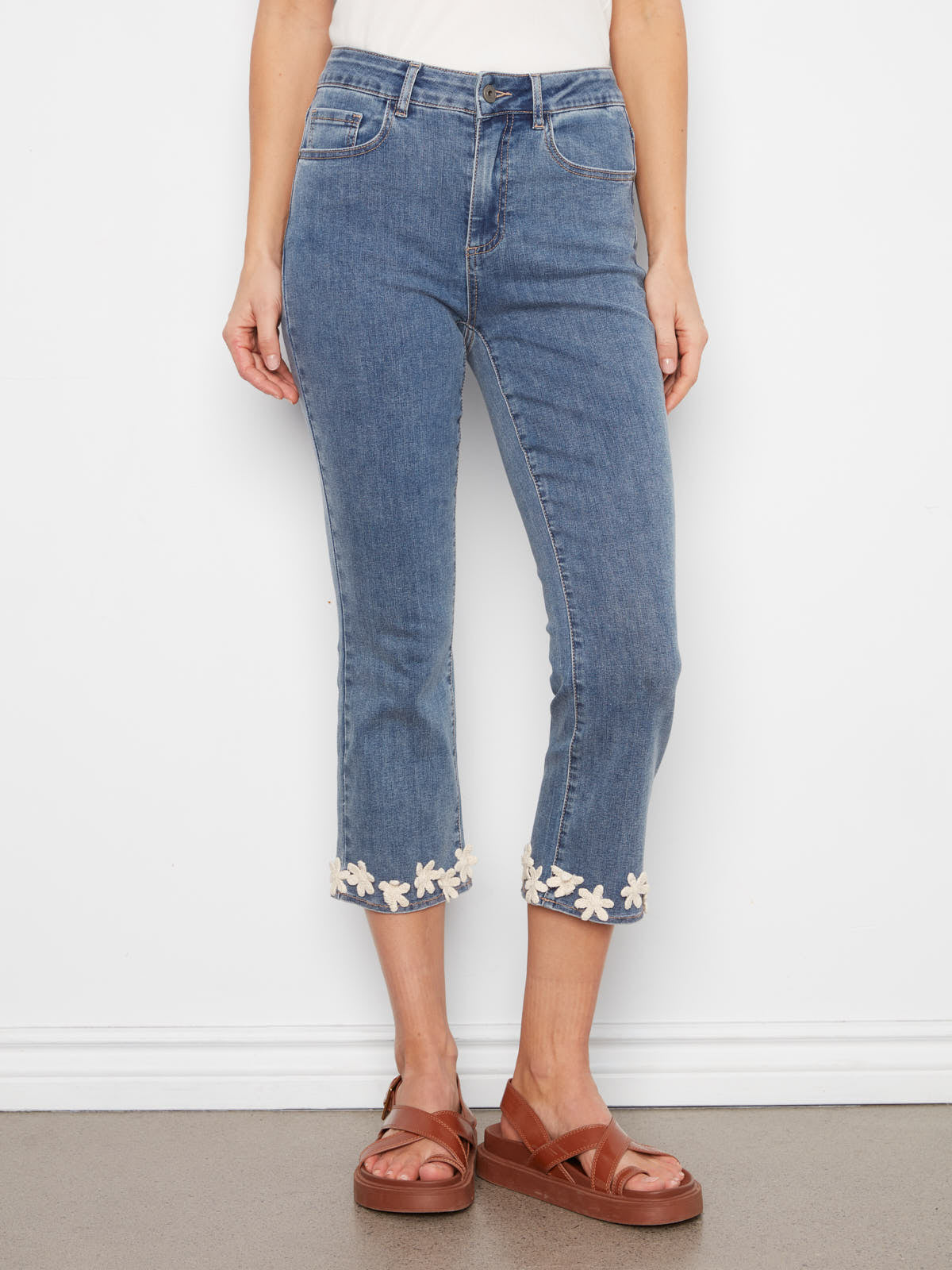 Charlie B Crochet Flower Hem Denim Capris in blue with floral crochet detail at hem, styled with brown sandals.