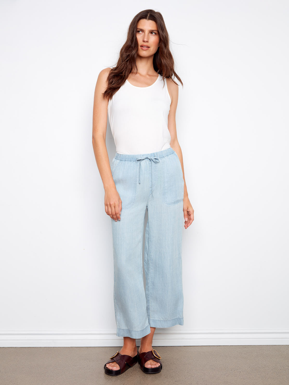 Light blue Charlie B Travel 4 Tencel Cropped Pant styled with a white sleeveless top and dark sandals.