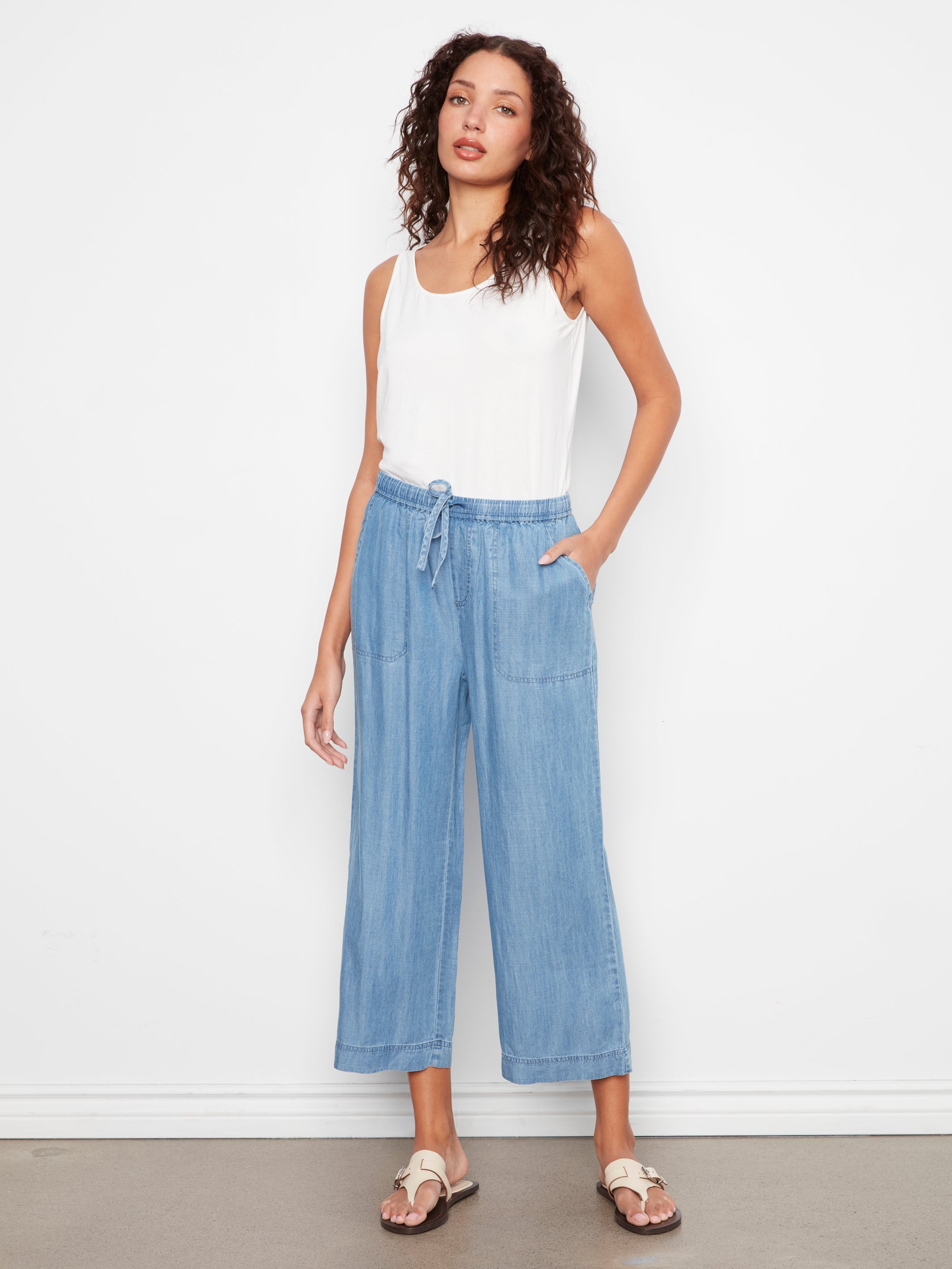 Light blue wide-leg denim pants with drawstring waist paired with a white sleeveless top and sandals.
