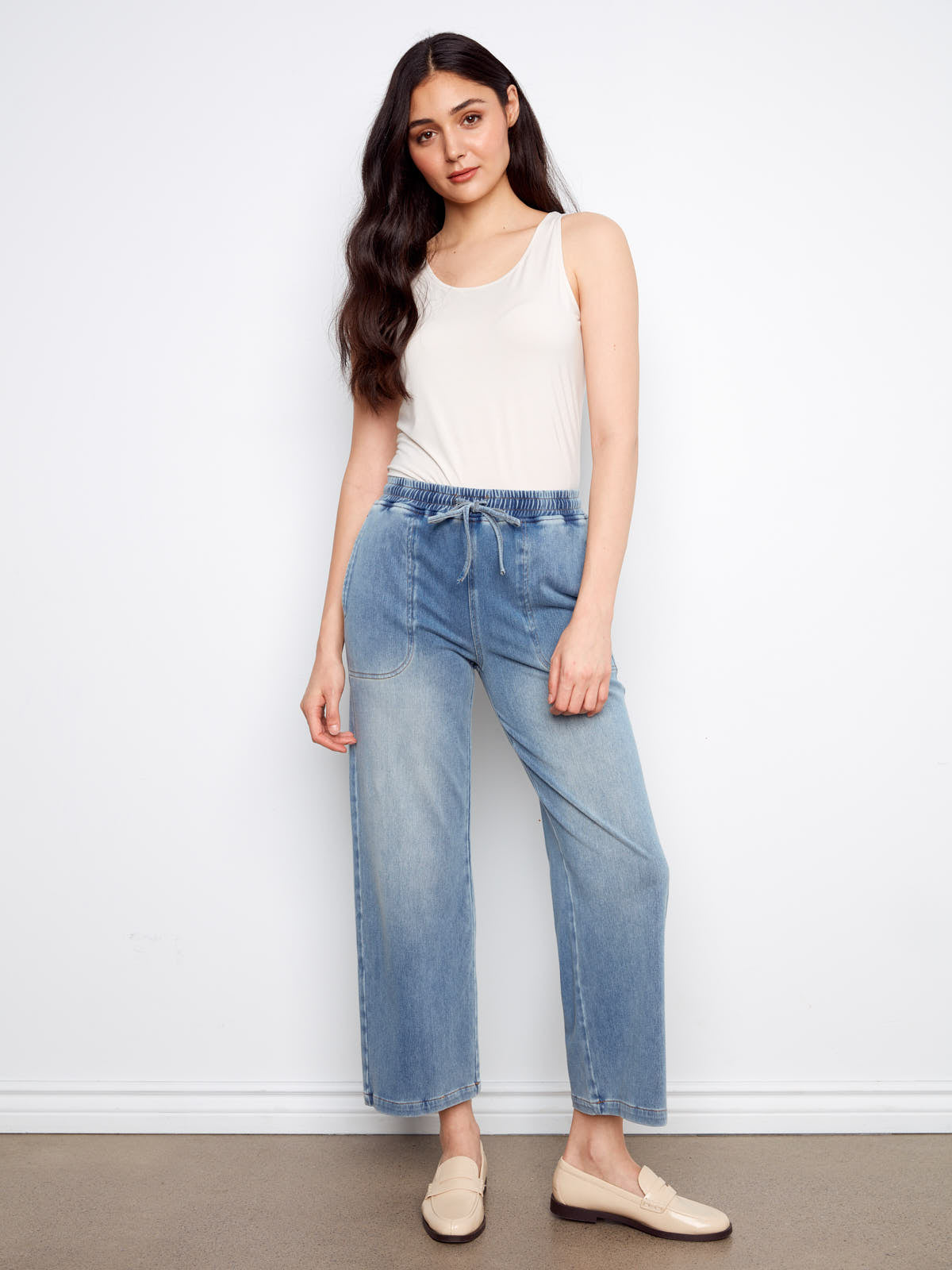 Light washed denim Charlie B Nautical Tie Waist Denim Pant styled with a white tank top and cream loafers by Charlie B.