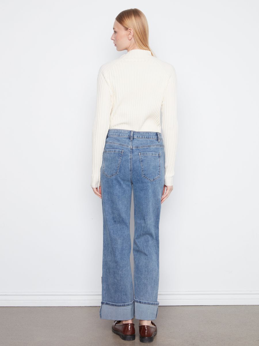 Light blue denim jeans with wide cuffs paired with a cream ribbed knit sweater against a white background.