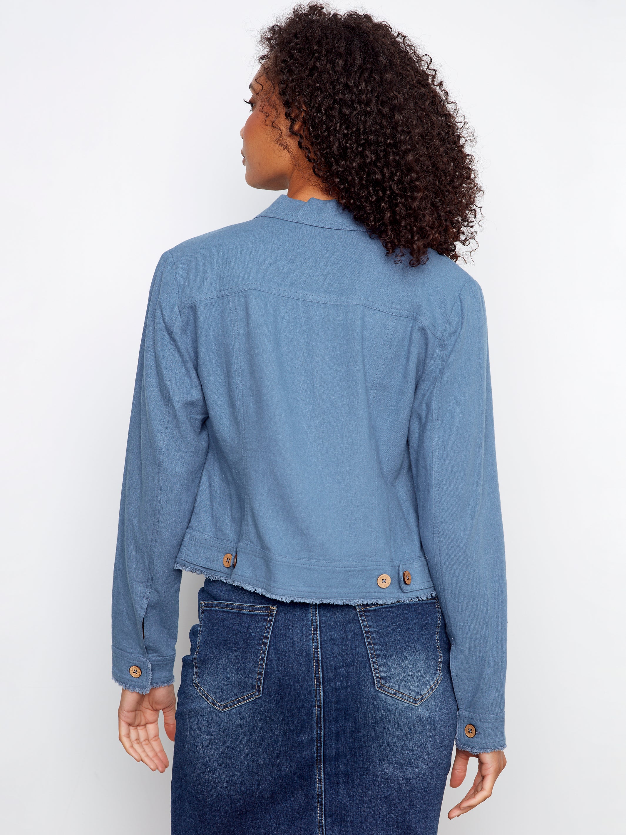 Back view of a blue Charlie B Linen Jacket paired with a denim skirt, featuring button details and long sleeves