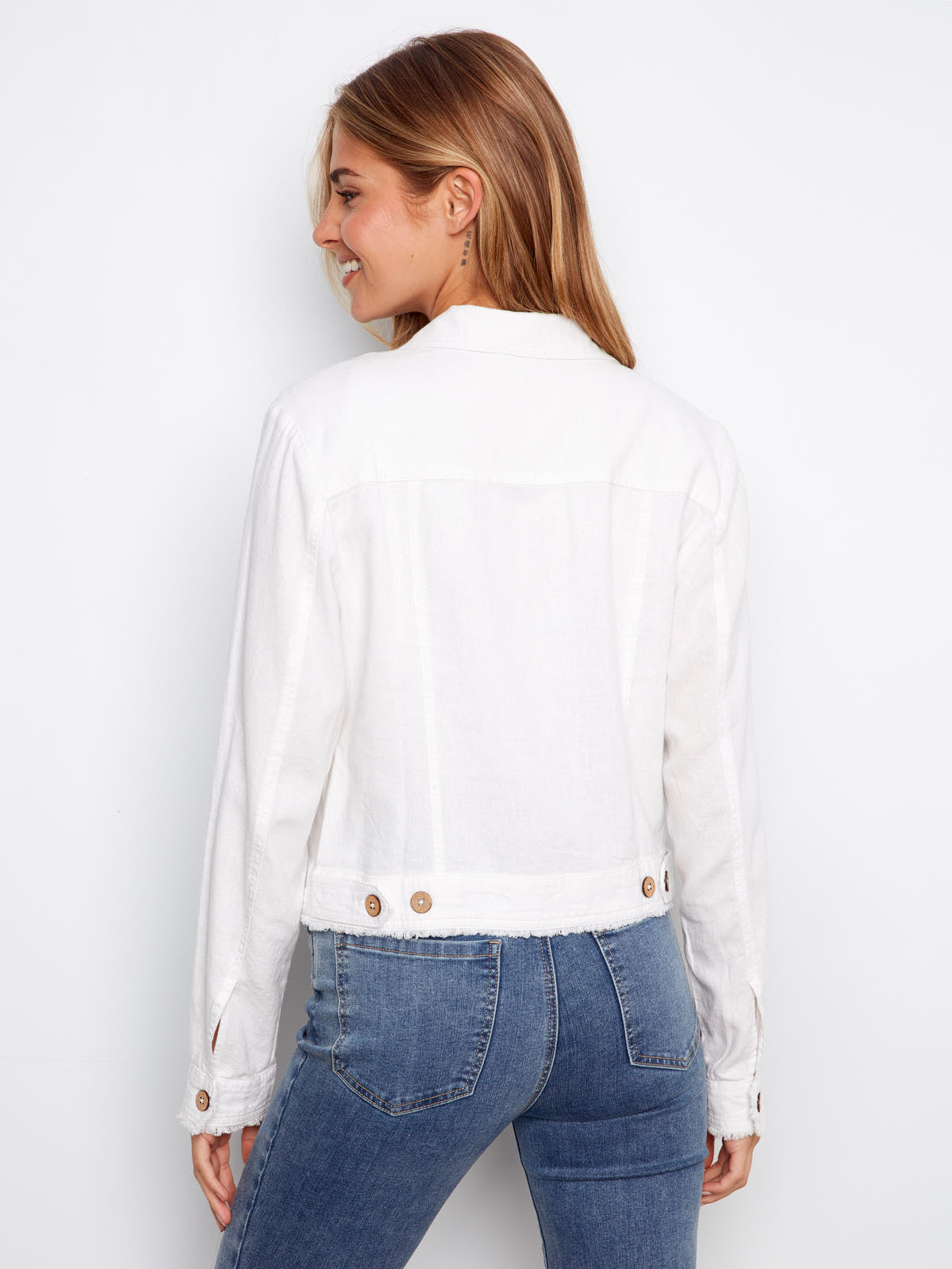 Back view of Charlie B Linen Jacket in white, paired with blue denim jeans, showcasing button details and texture.