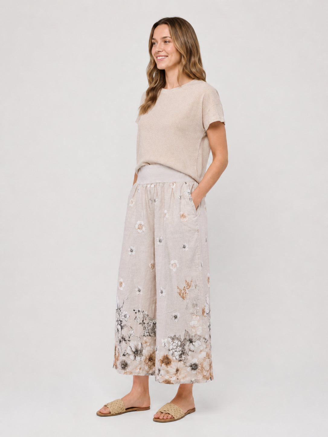 Beige short-sleeve top paired with wide-leg floral print pants and woven slide sandals on a light background.