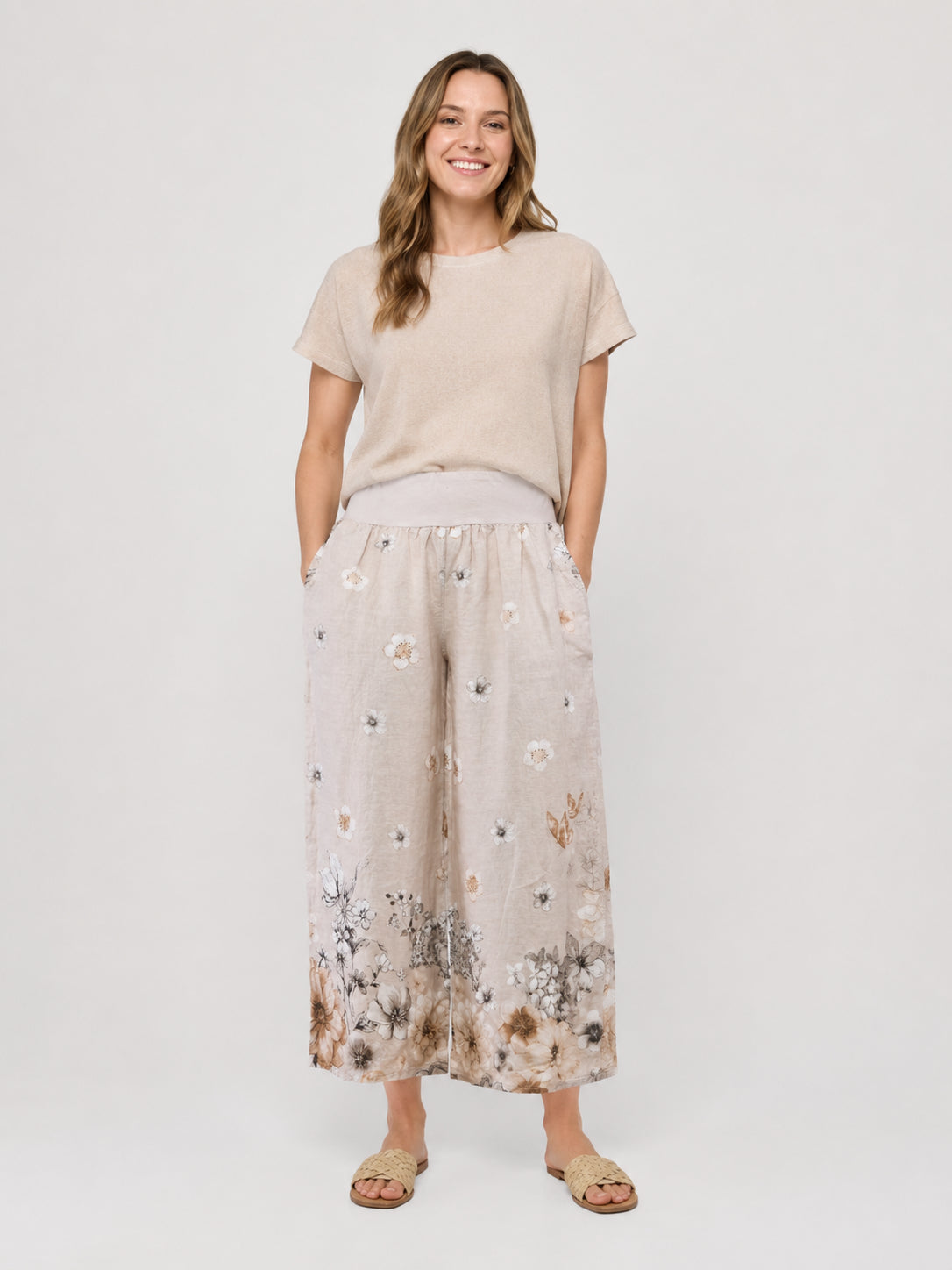 Light beige short-sleeve top paired with wide-leg beige pants featuring a floral pattern along the bottom hem.