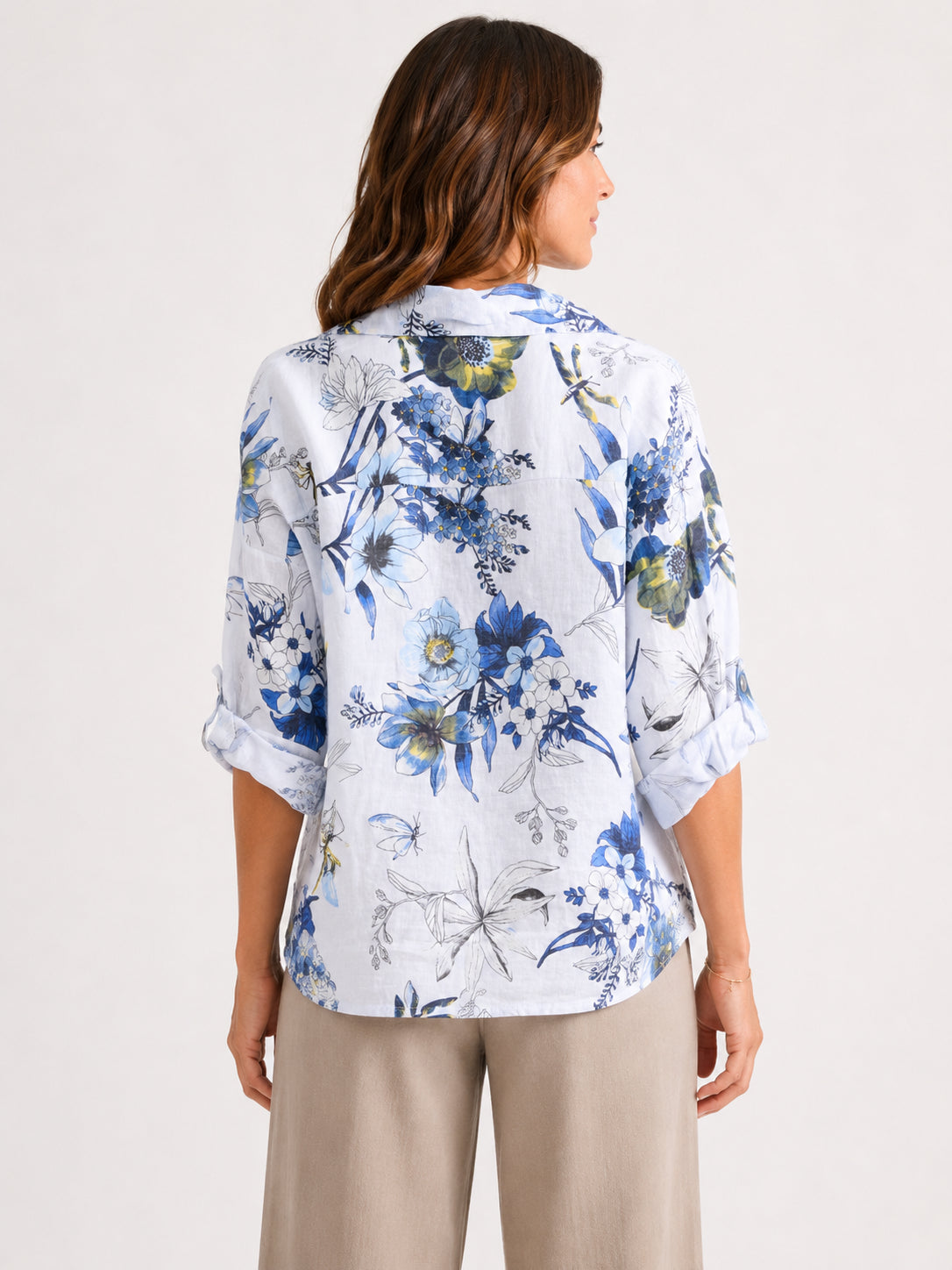 Back view of a white button-up shirt with blue and green floral print paired with beige pants.