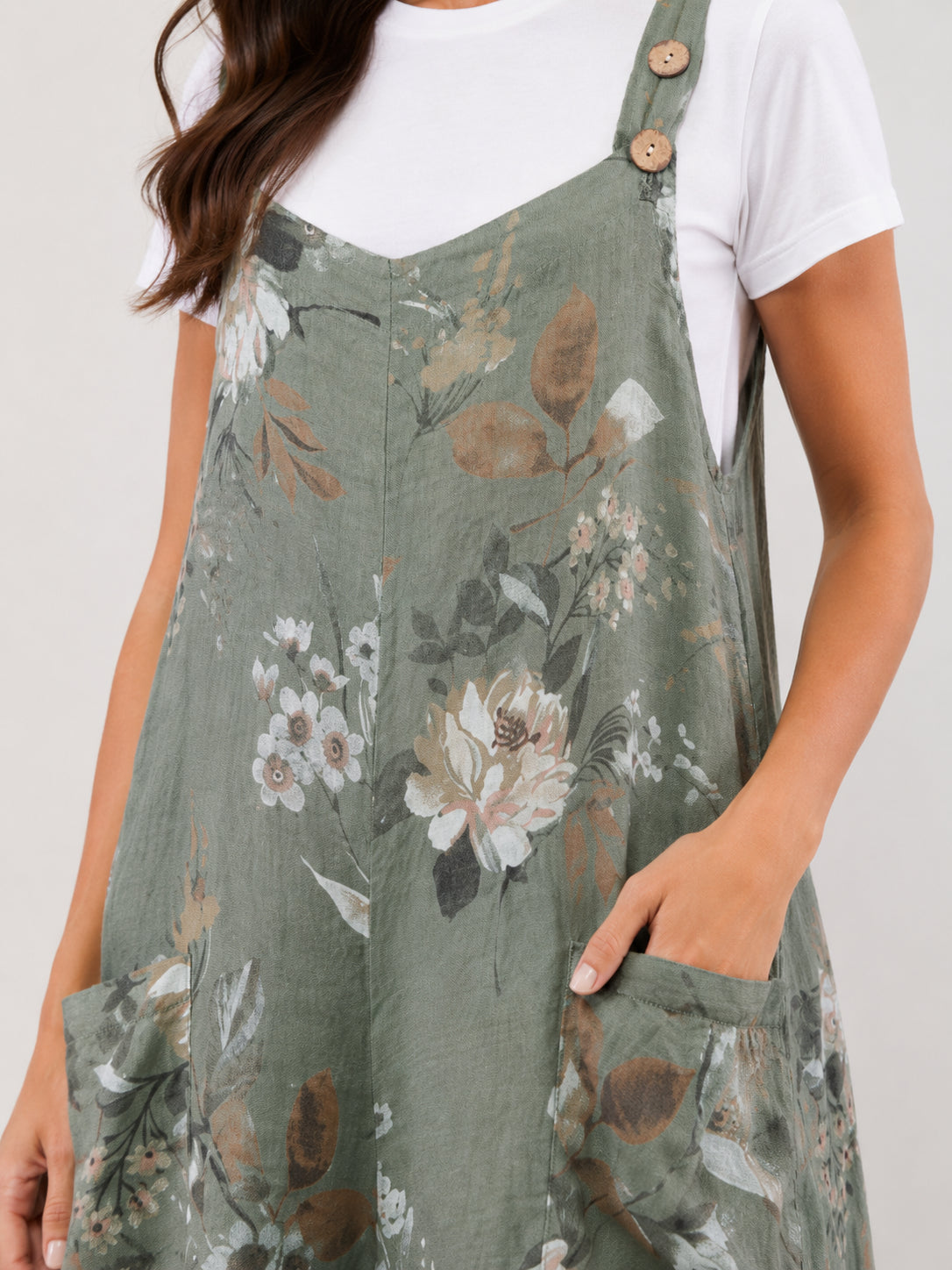 Green floral patterned dress with wooden button straps and front pockets over a white short sleeve top