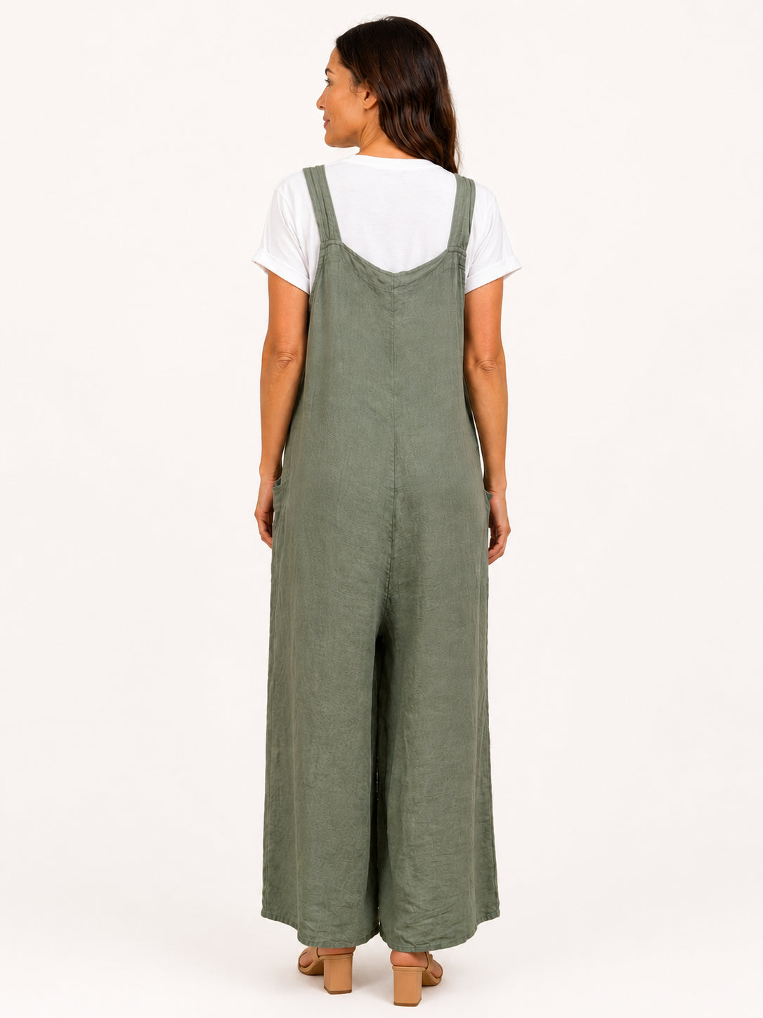 Back view of olive green wide-leg jumpsuit layered over a white short-sleeve top with block heel sandals.