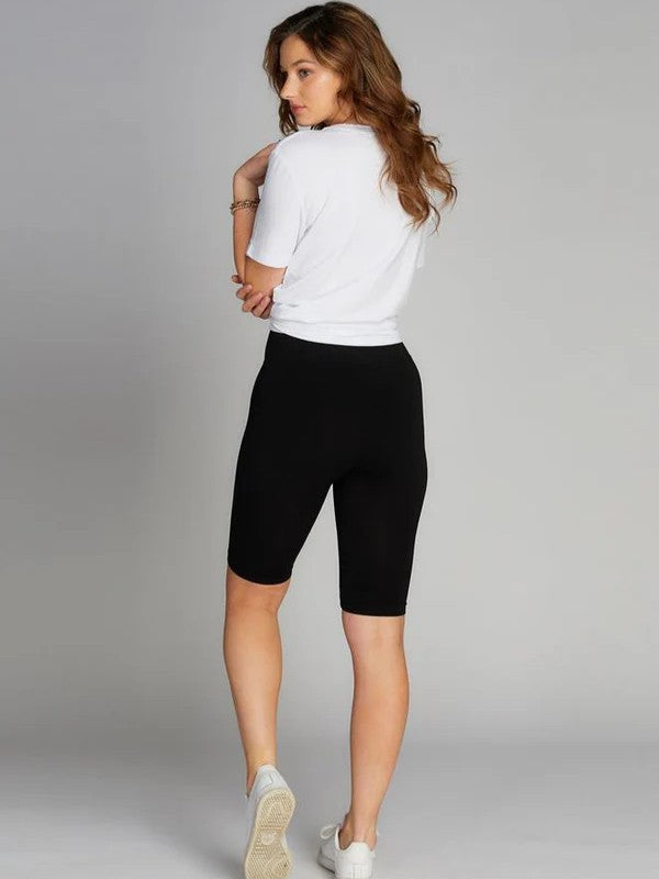 Back view of a figure in a white short-sleeve top and black knee-length fitted shorts with white sneakers.