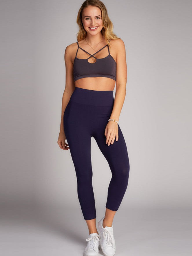 Navy 3/4 High Waist Bamboo Leggings by Coast To Coast Trading styled with a dark strappy sports bra and white sneakers