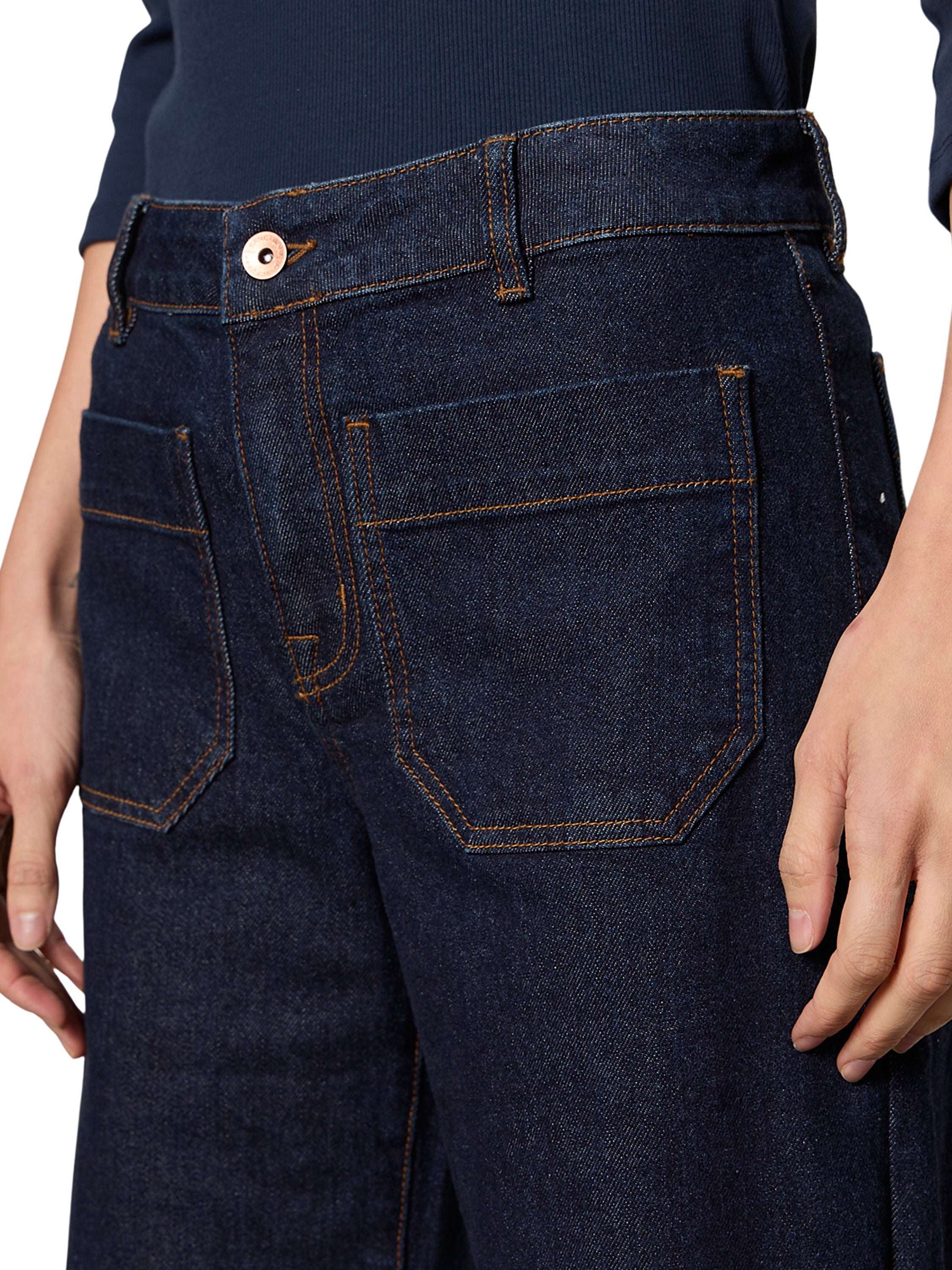 Close-up of Sanctuary Marine Double Pocket 27” Denim Pant in dark blue denim with contrast stitching and copper button closure