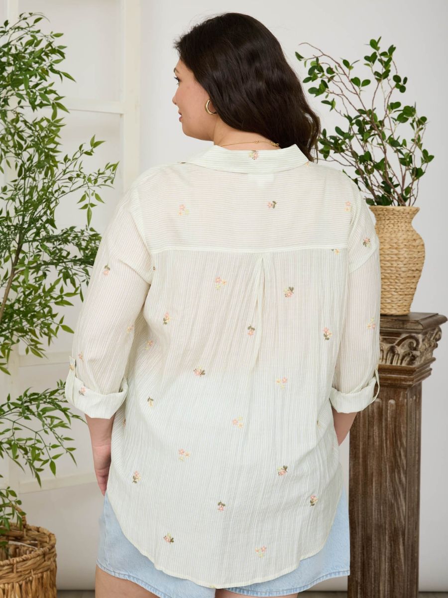 Light cream long-sleeve top with subtle floral embroidery and rolled sleeves shown from the back