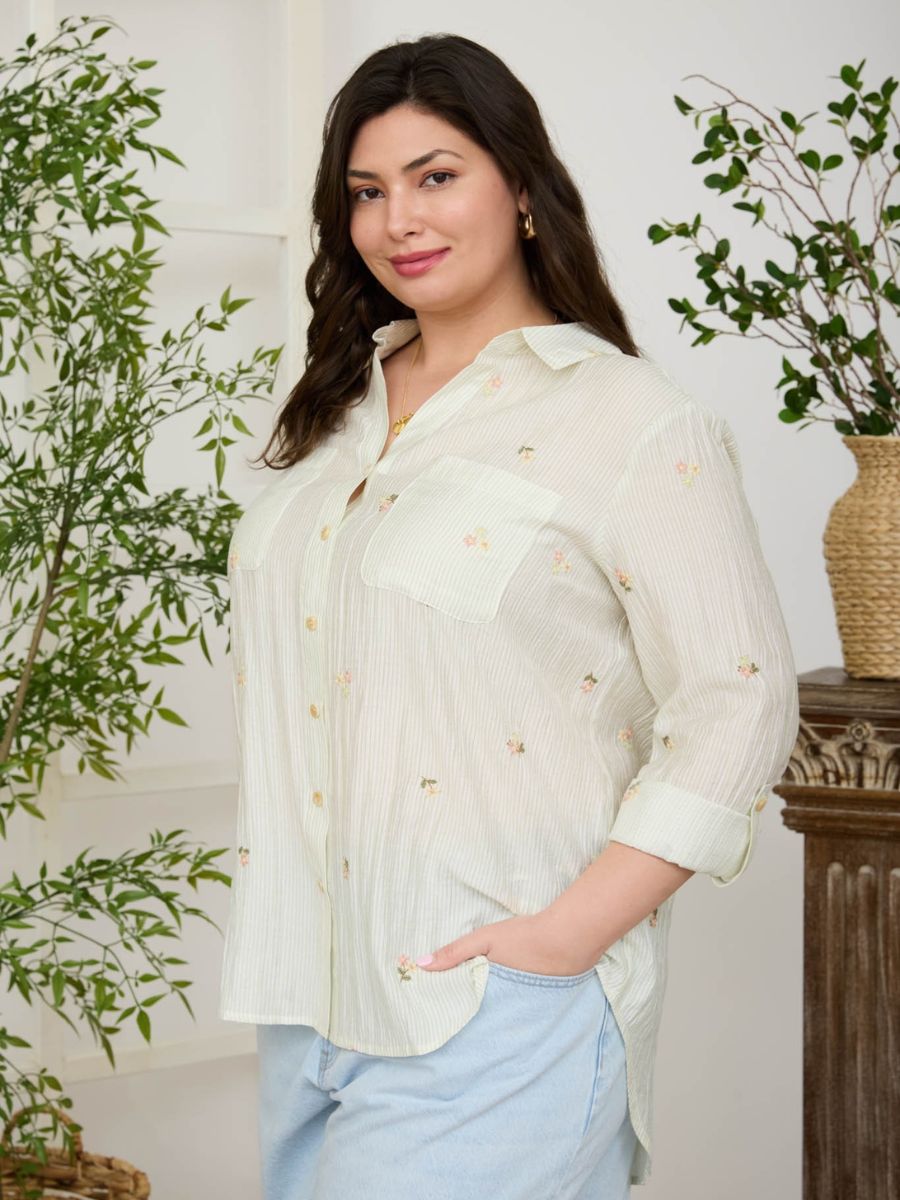 Light-colored long-sleeve button-up shirt with small floral embroidery paired with light blue denim bottoms
