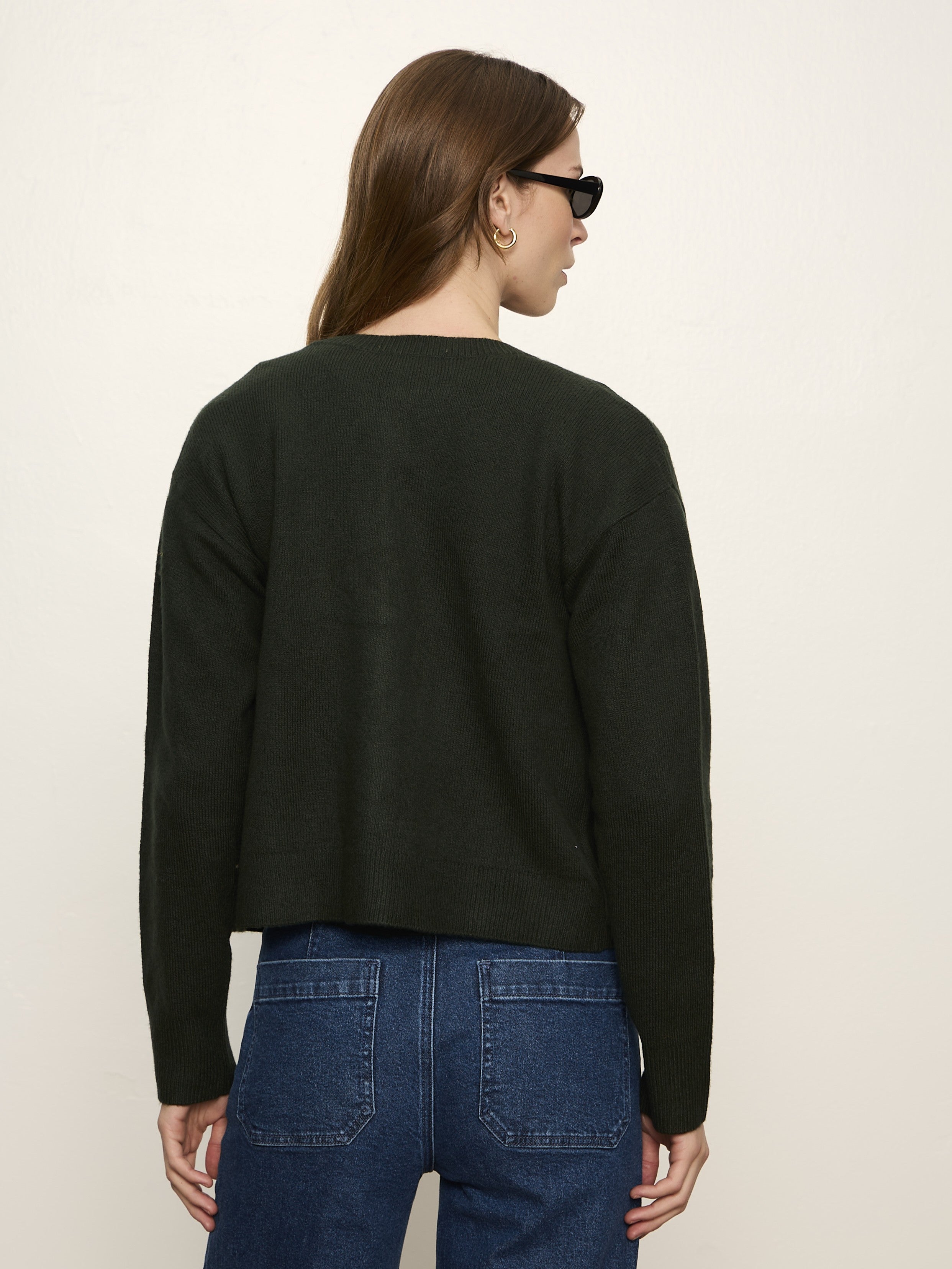 Dark green long-sleeve sweater paired with blue denim jeans, shown from the back on a neutral background.