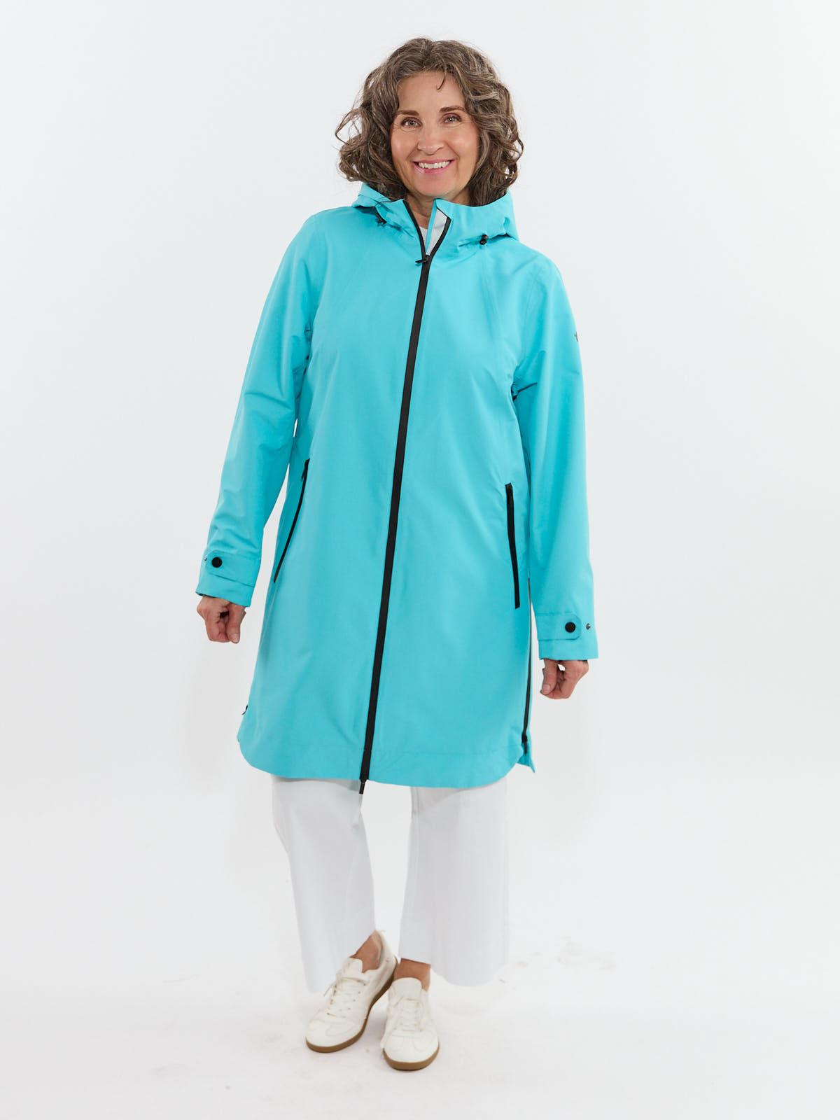 Light blue hooded waterproof jacket with front zipper and side pockets worn over white pants and sneakers.