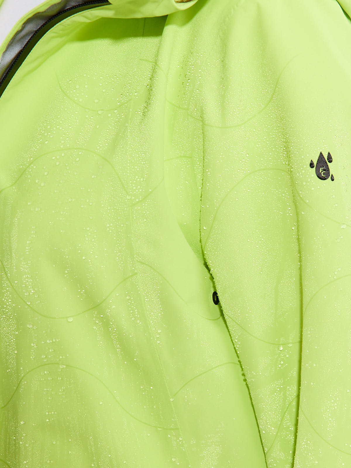 Close-up of lime green waterproof outerwear fabric with water droplets and a small black water droplet logo.