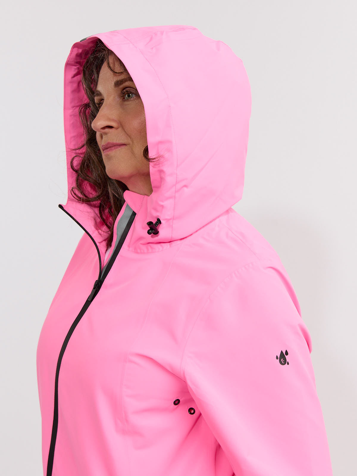 Side view of a person wearing a bright pink hooded jacket with black zipper and drawstring details