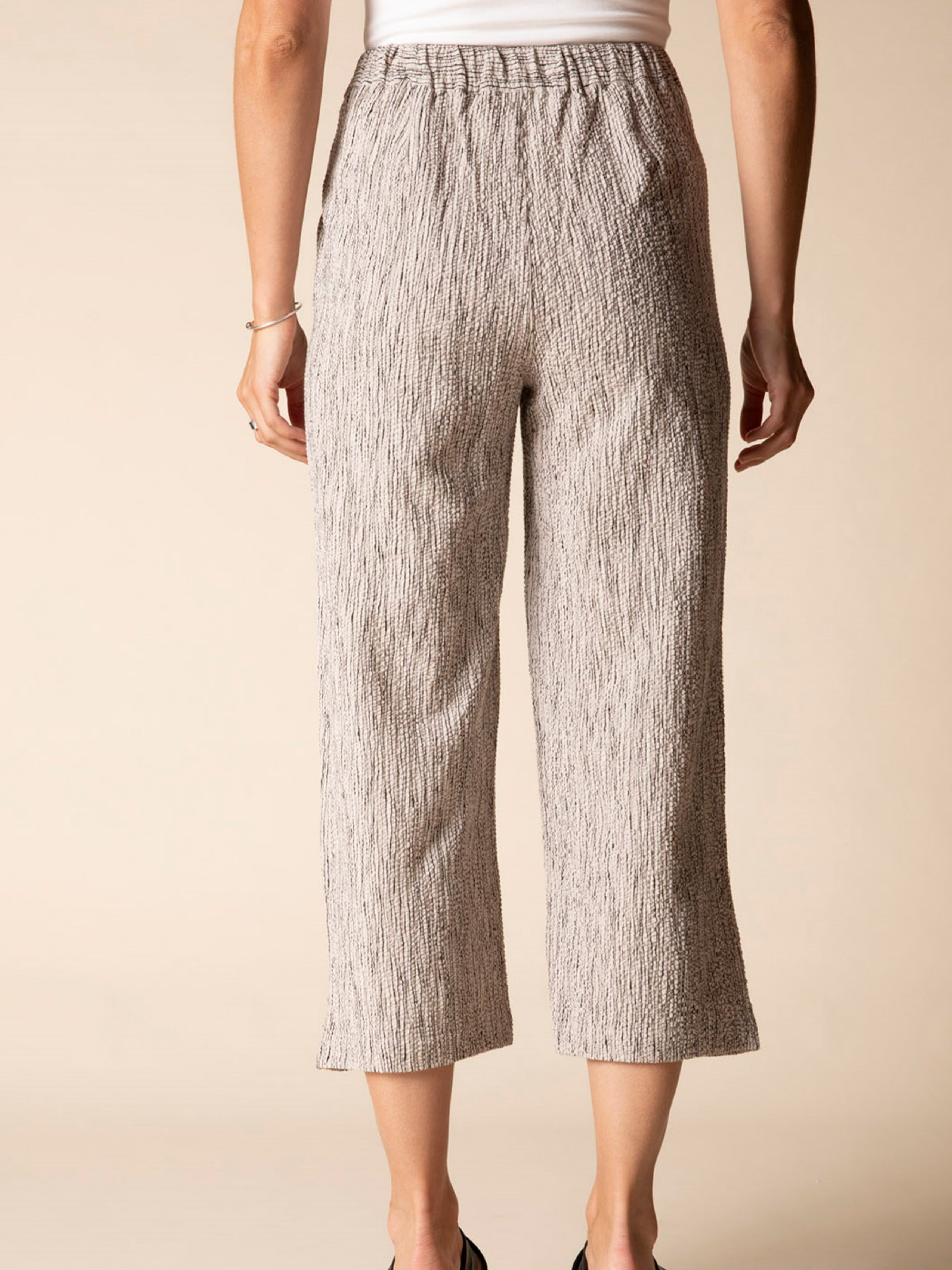 Rear view of beige textured Habitat Amalfi Floral Crinkle Stripe 24" Crop Pants on model against plain background