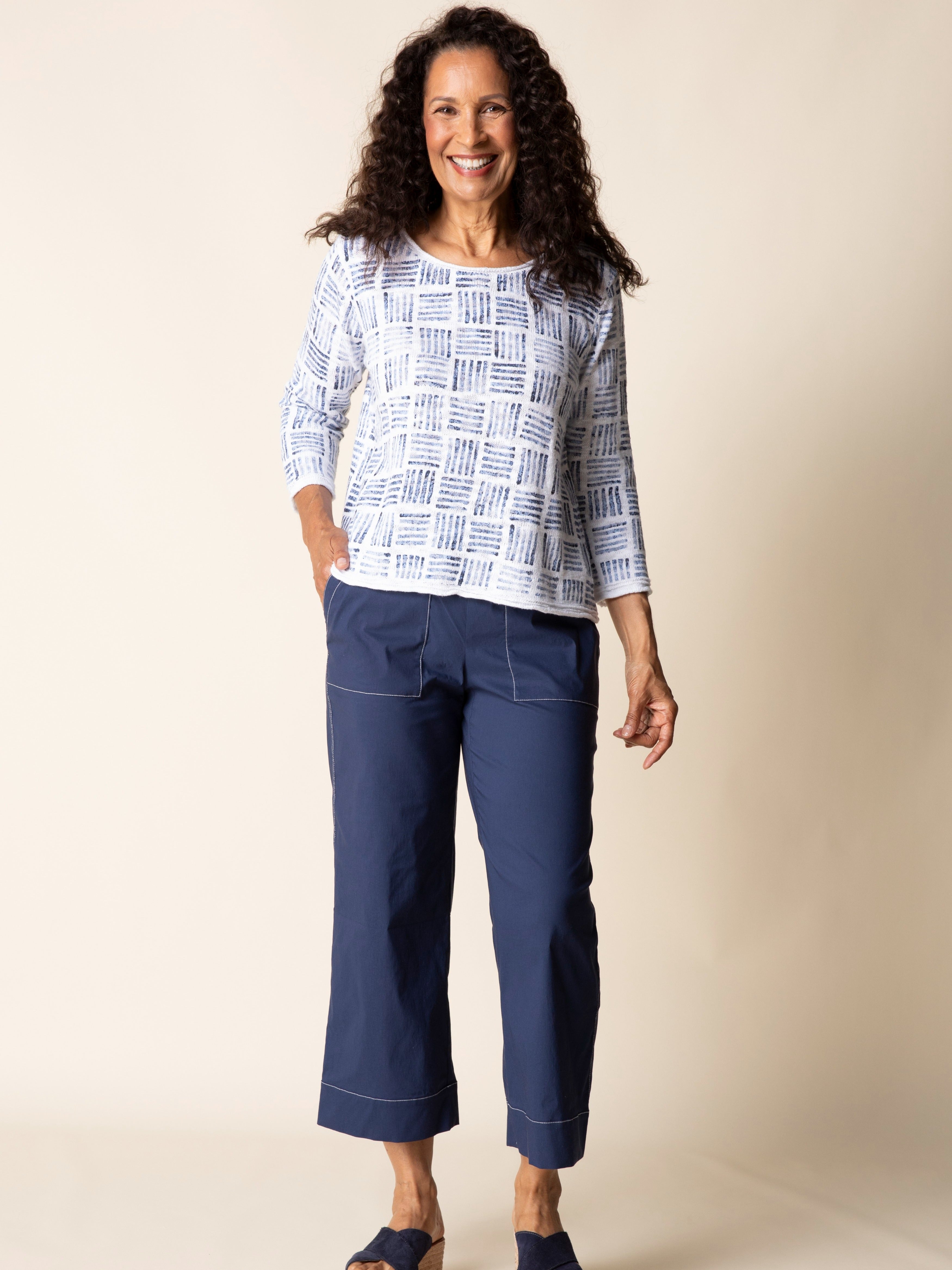 Woman smiling in a blue and white Habitat Stamped Drift Cotton Crewneck Sweater paired with navy pants and sandals