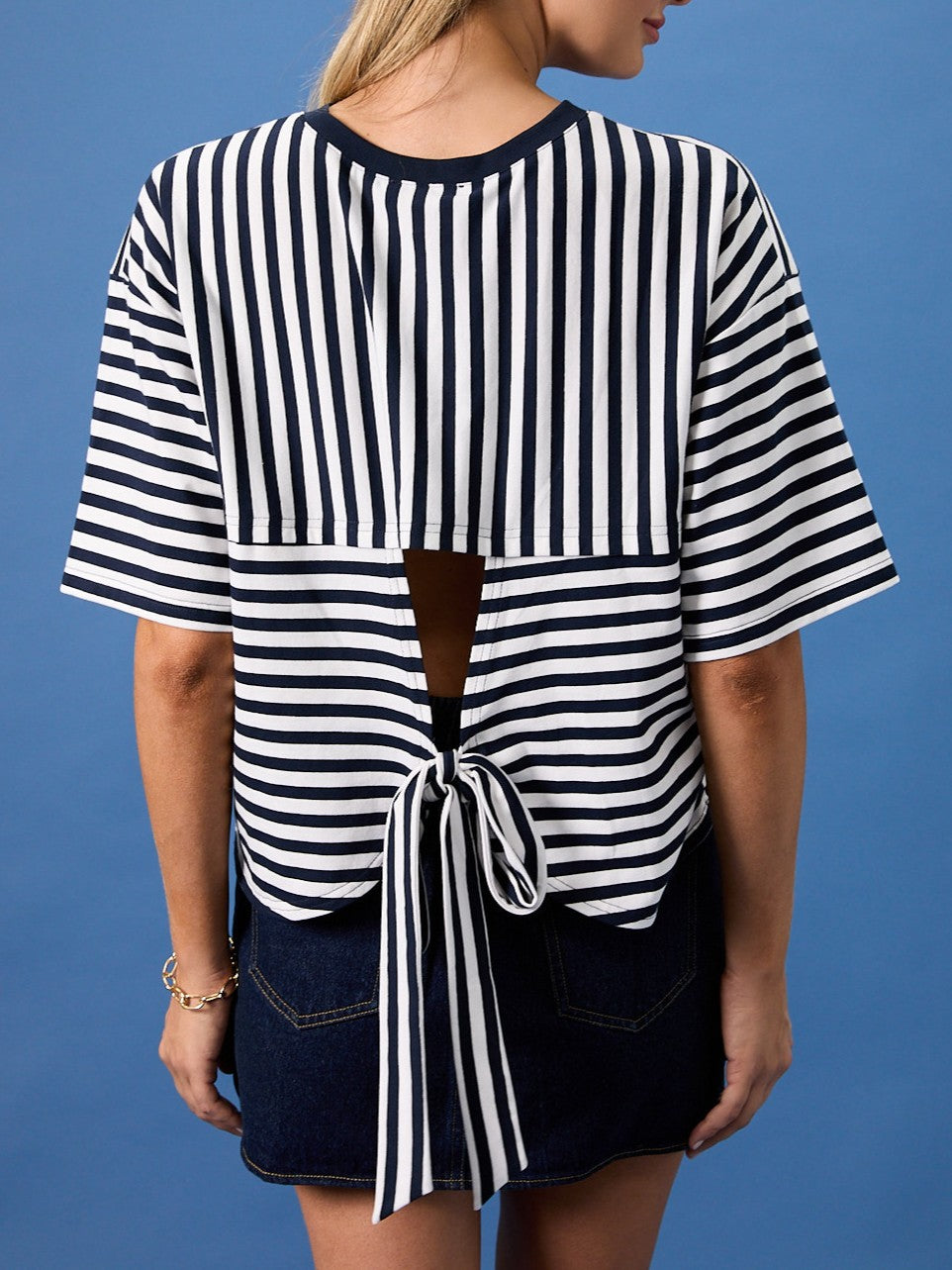Navy and white striped short-sleeve top with open back and tie detail, paired with a dark denim skirt.