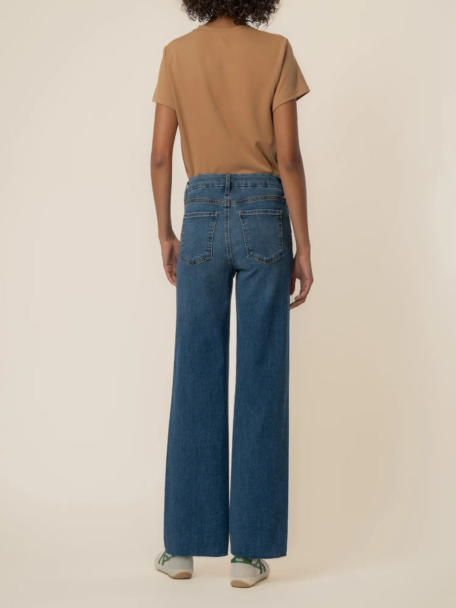 Back view of Kut from the Kloth Meg 29” Wide Denim Jeans in medium blue with a tan top and casual shoes.