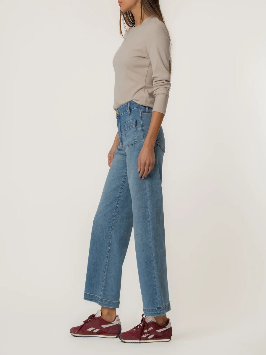 Kut from the Kloth Meg Double Trouble 27” Finish Jeans in light blue denim styled with a beige long sleeve top and red sneakers