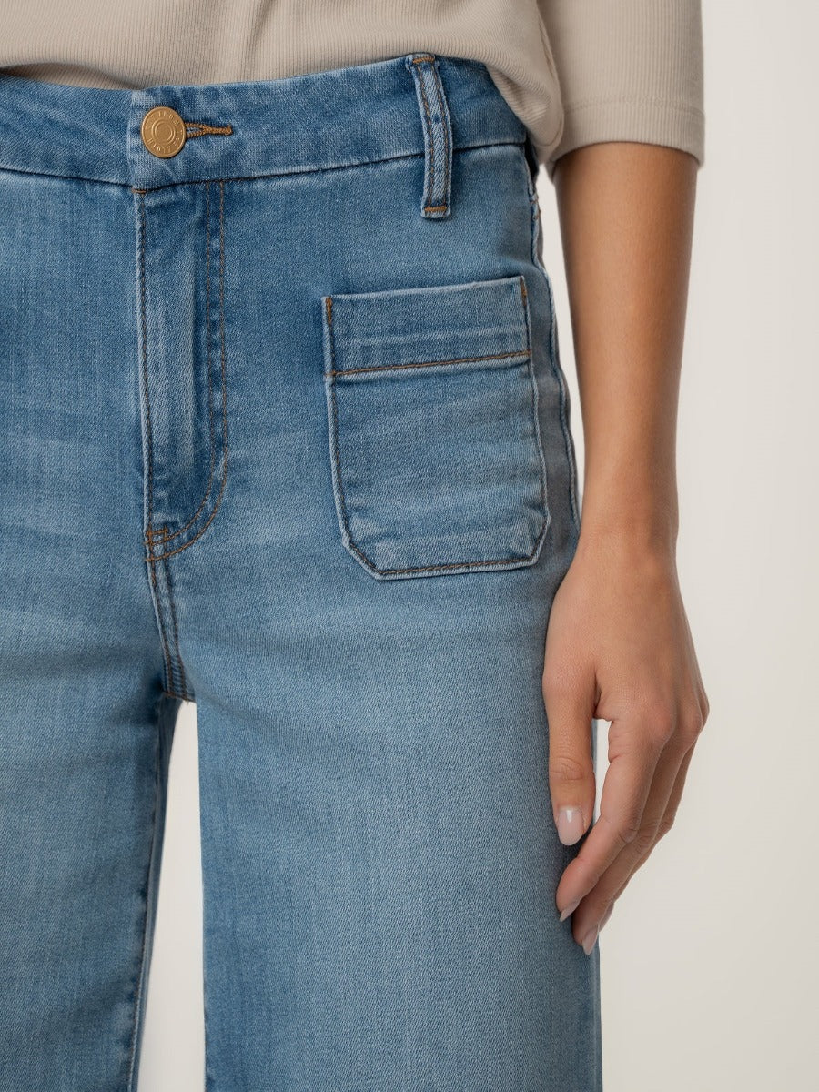 Close-up of light blue denim Kut from the Kloth Meg Double Trouble 27” Finish Jeans with side pocket and beige top.