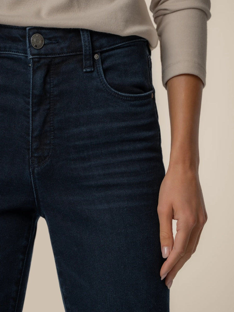 Close-up of dark denim Kut from the Kloth Ana 33” Flare Denim Jeans paired with a beige long sleeve top