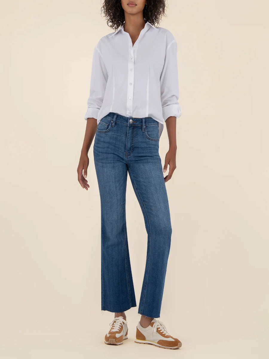 Kut from the Kloth Kelsey High Rise Flare Jeans in medium denim paired with white button-up shirt and casual sneakers