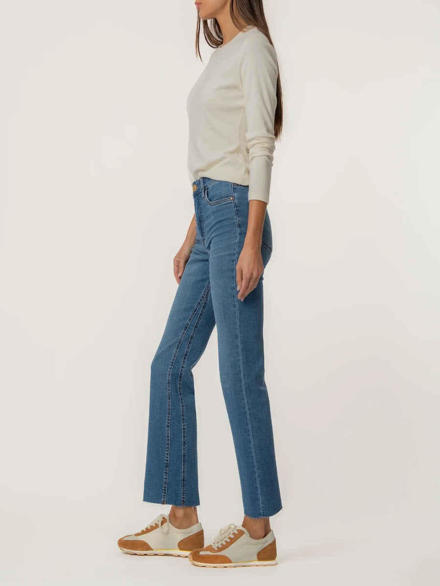 Kut from the Kloth Kelsey High Rise Ankle Flare Jeans in medium blue denim styled with casual sneakers and a light sweater.