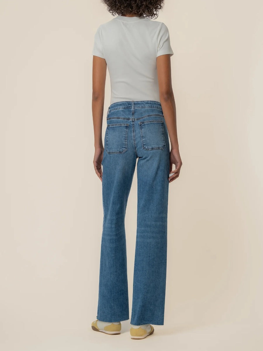 Back view of Kut from the Kloth Maya High Rise 31” Wide Leg Jeans in blue denim on model against beige background
