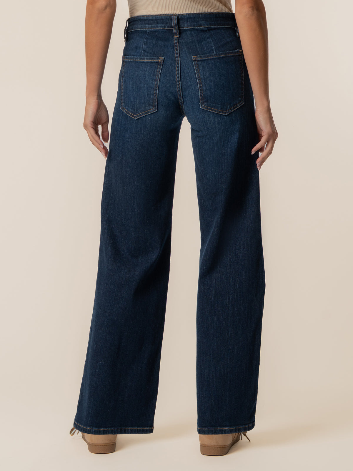 Rear view of dark blue wide-leg denim jeans with patch pockets and cuffed hems