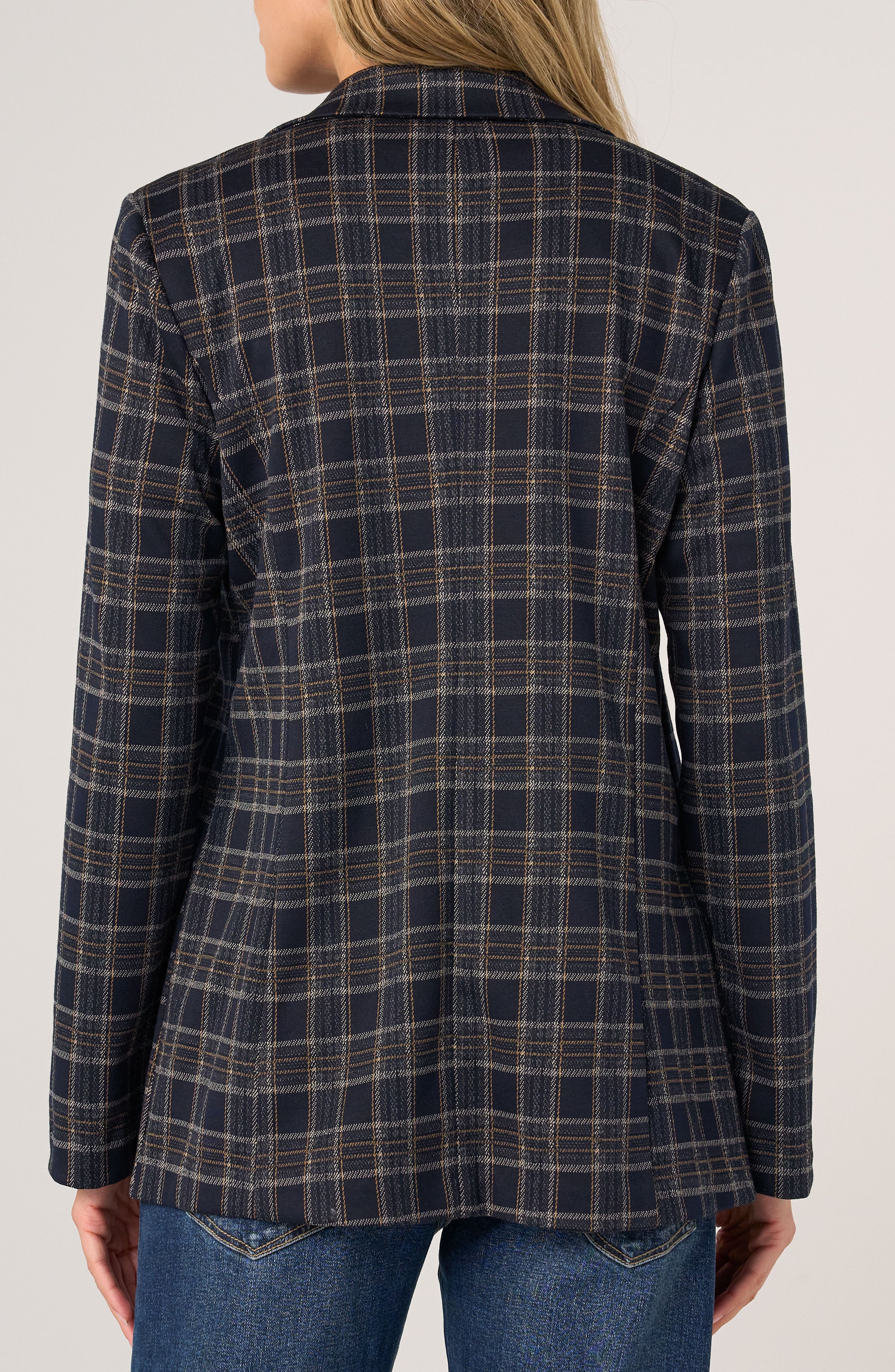 Back view of a navy plaid tailored jacket paired with blue denim jeans against a plain background.