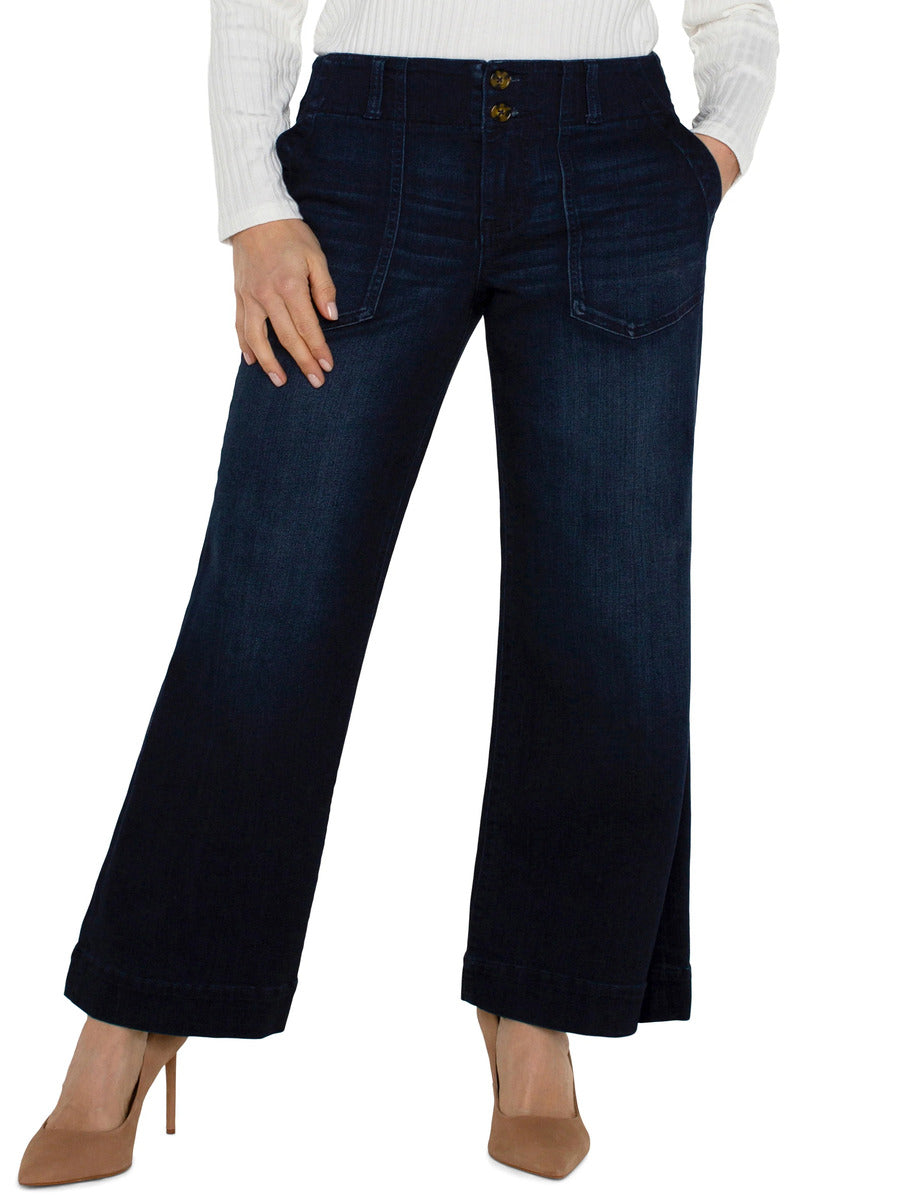 Dark denim wide-leg pants with patch pockets and cuffed hems paired with beige pointed heels