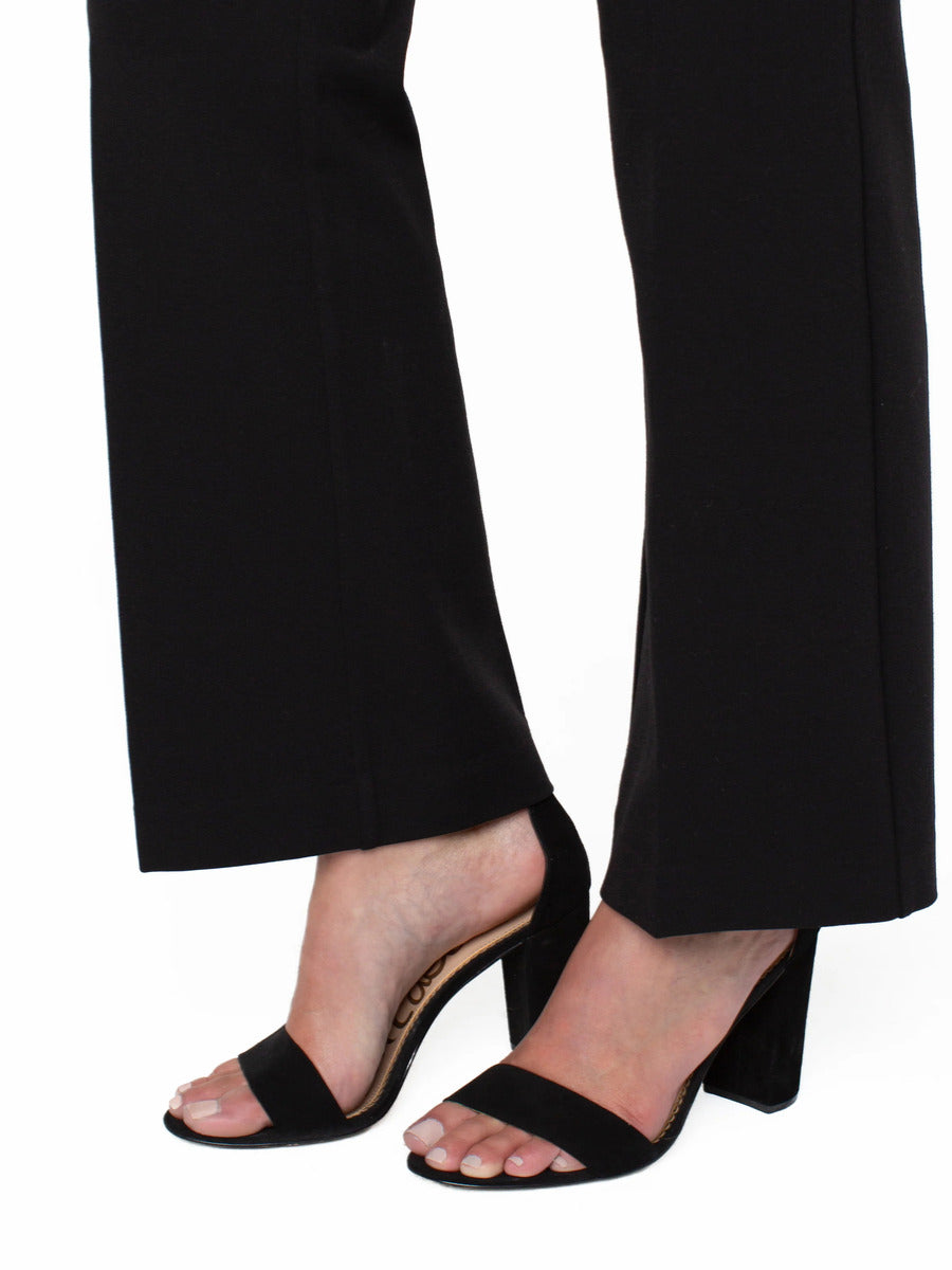 Black high-heeled sandals with block heels paired with black wide-leg pants cropped above the ankles.