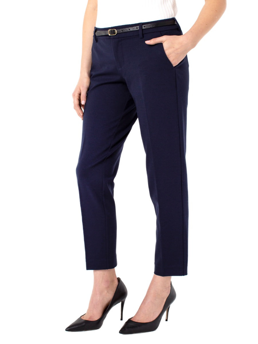Navy tailored Liverpool Kelsey Solid 29” Pant styled with a slim black belt and black high heels by Liverpool
