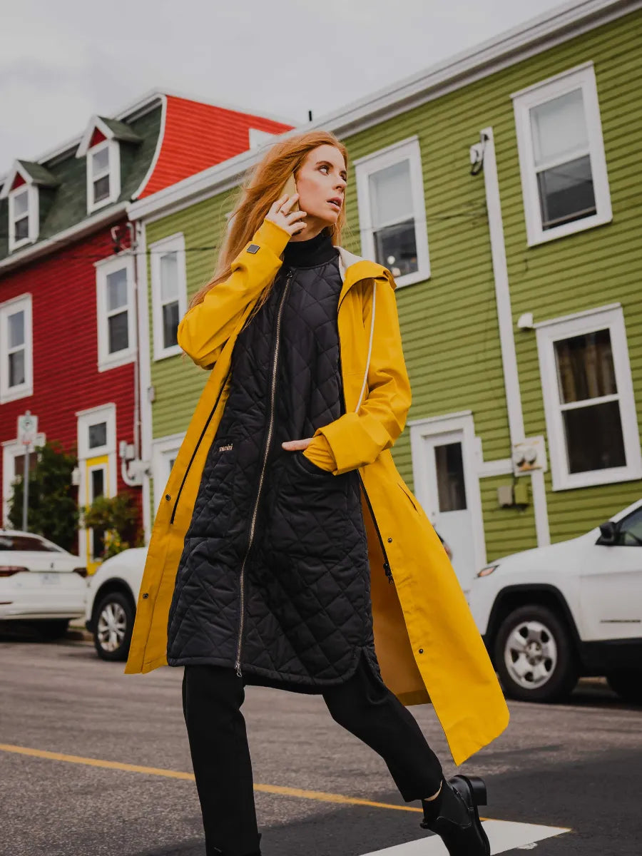 Black quilted Mernini Quilted Double Pocket Vest layered under a yellow coat by MERNINI/ROCK RAIN INC.