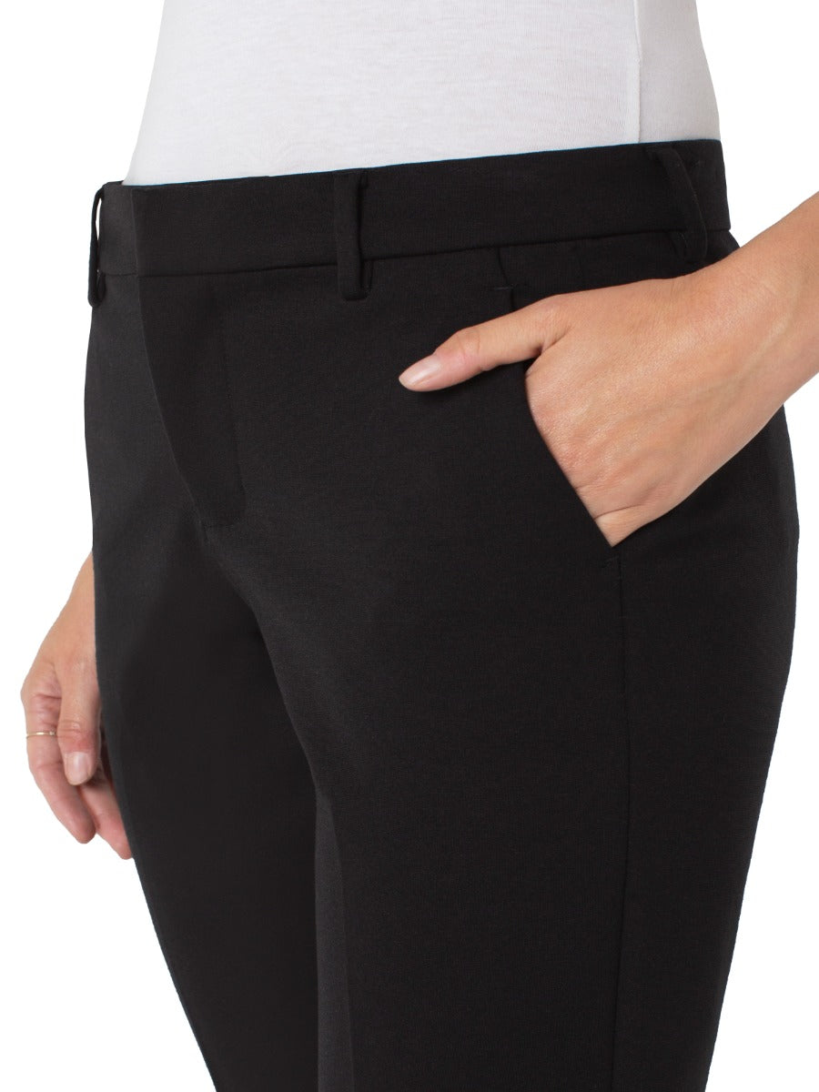 Close-up of Liverpool Petite Kelsey 27” Solid Pant in black fabric with hand in pocket, styled with a white top.