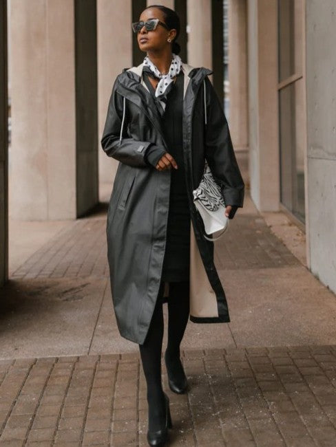 Black waterproof coat with hood and drawstrings styled with scarf and handbag in urban setting, Mernini 48” Length Waterproof Raincoat by MERNINI/ROCK RAIN INC