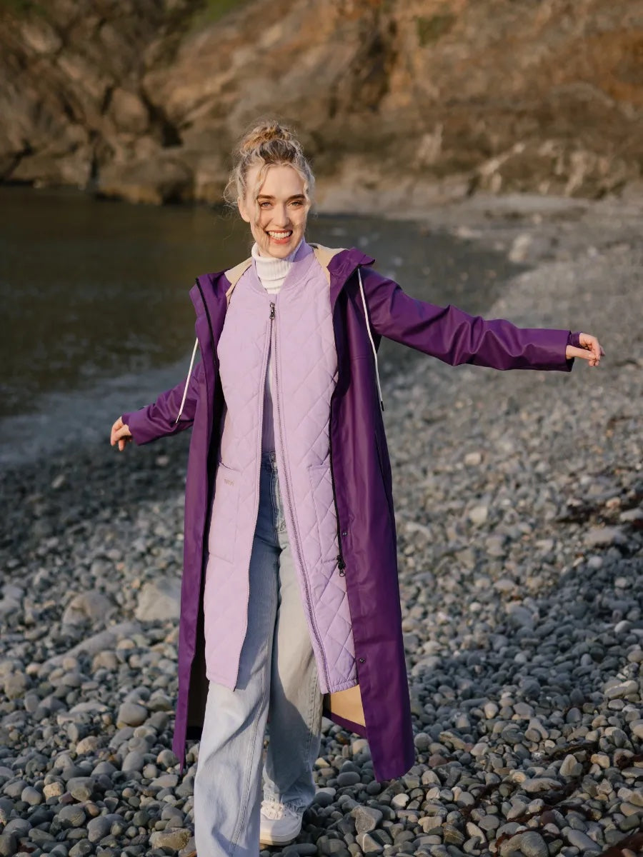 Light purple Mernini 48” Length Waterproof Raincoat by MERNINI/ROCK RAIN INC on rocky beach outdoor setting