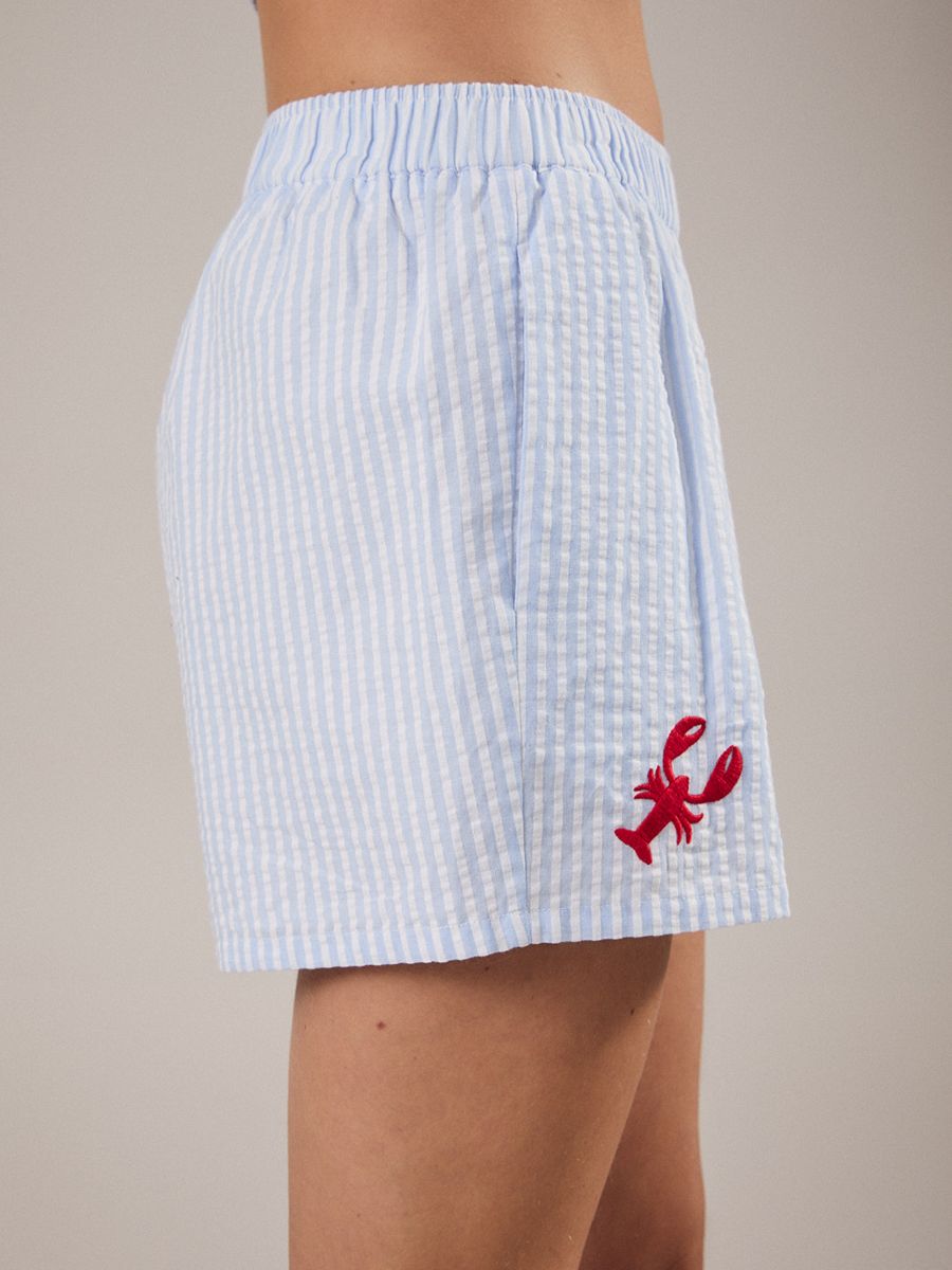 Light blue and white striped shorts with an elastic waistband and small red lobster embroidery near the hem.
