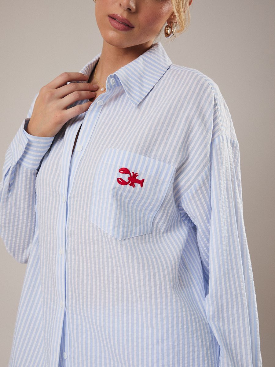Light blue and white striped button-up shirt with a small red lobster embroidered on the chest pocket