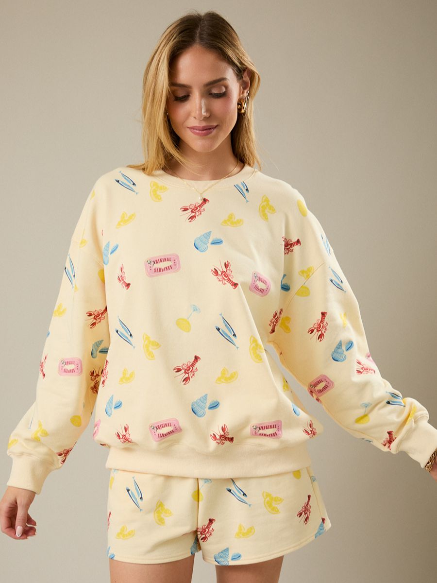 Woman wearing a cream-colored pajama set with colorful graphics on a neutral background