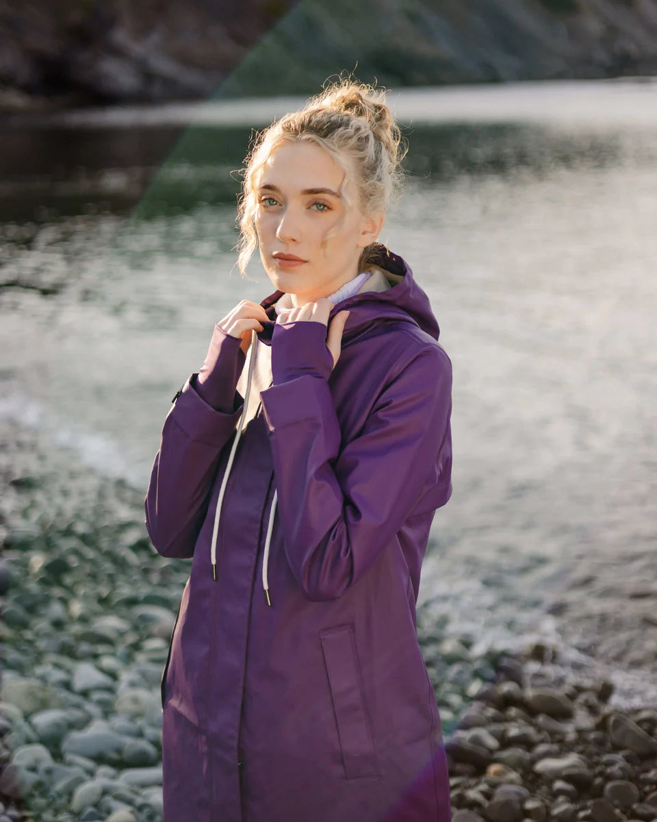 Light purple hooded outerwear jacket with drawstrings, worn near a rocky riverside background in soft natural light.
