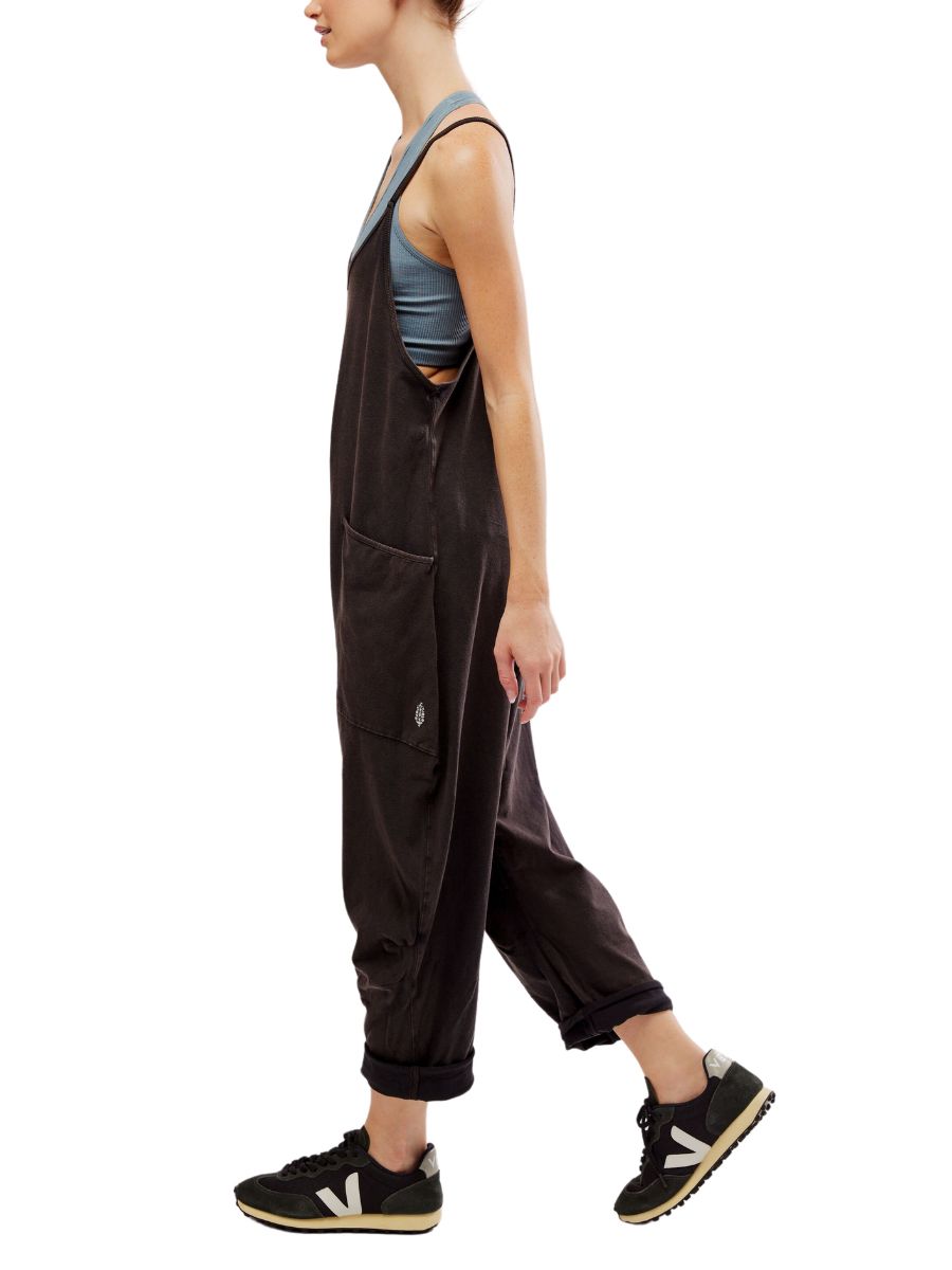 Side view of a person wearing a black Free People Hot Shot Onesie with rolled cuffs and black sneakers