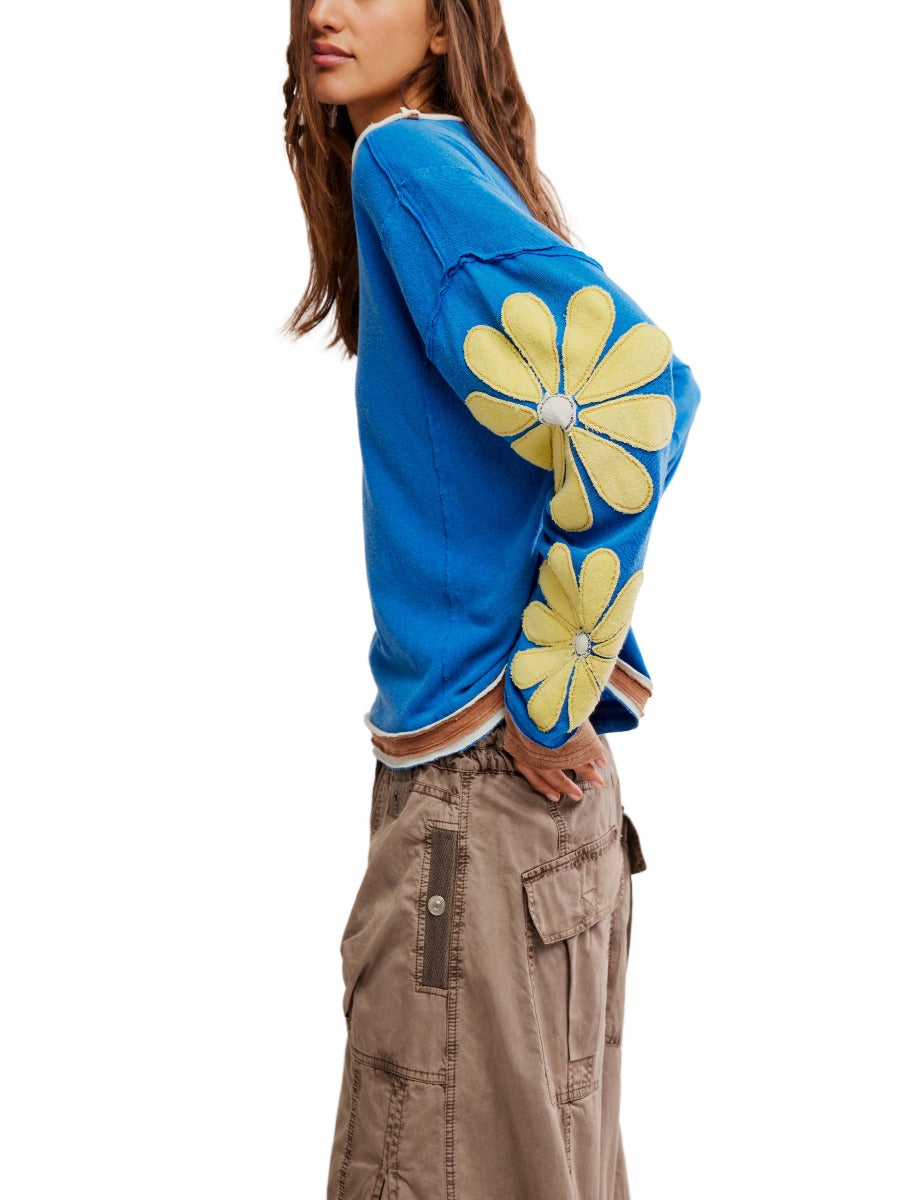 Free People You’re A Star Floral Top in blue with large yellow flower appliques on sleeves, styled with cargo pants.