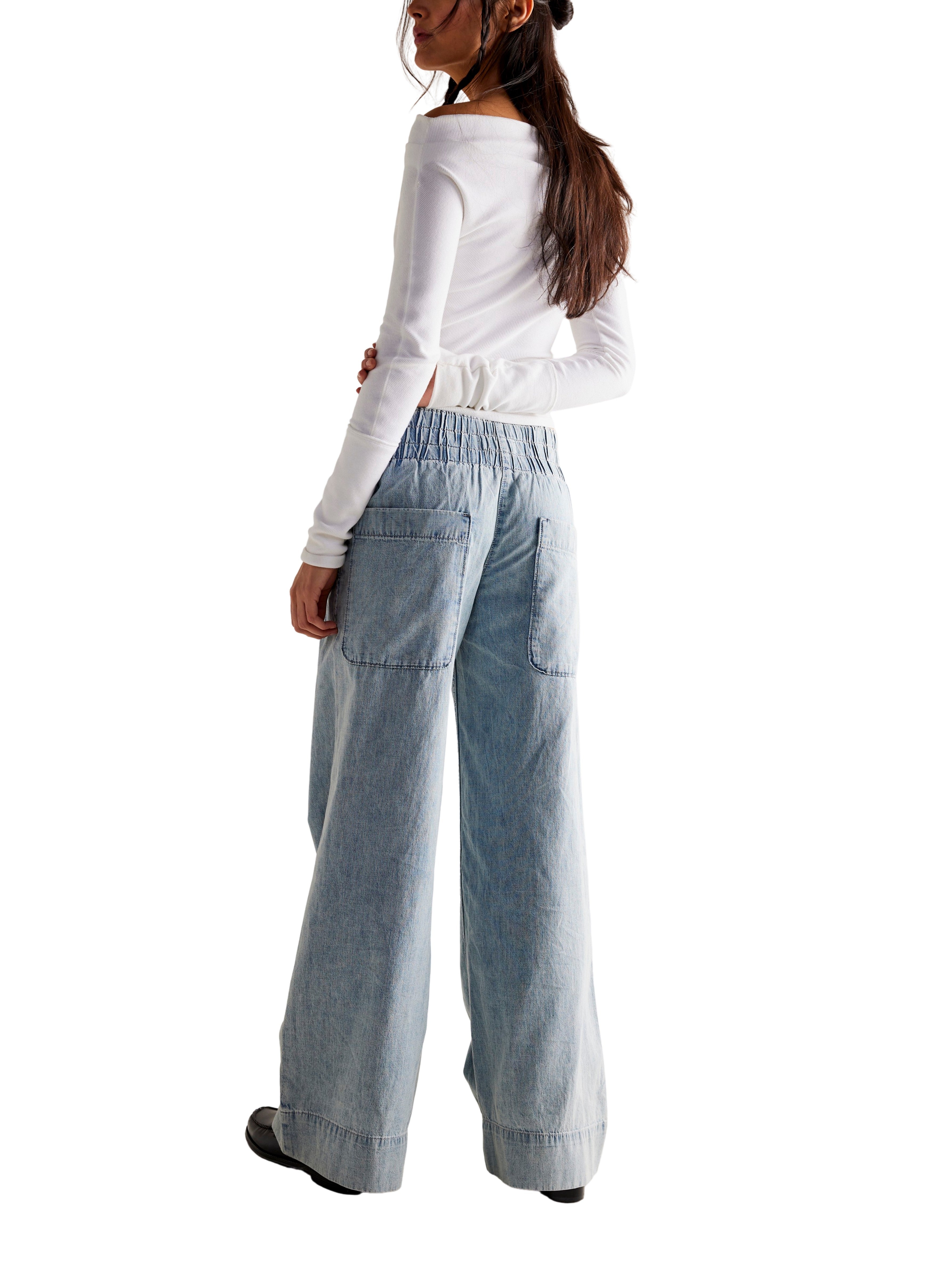 Light blue wide-leg denim pants with elastic waistband and large back pockets paired with a long-sleeve white top.